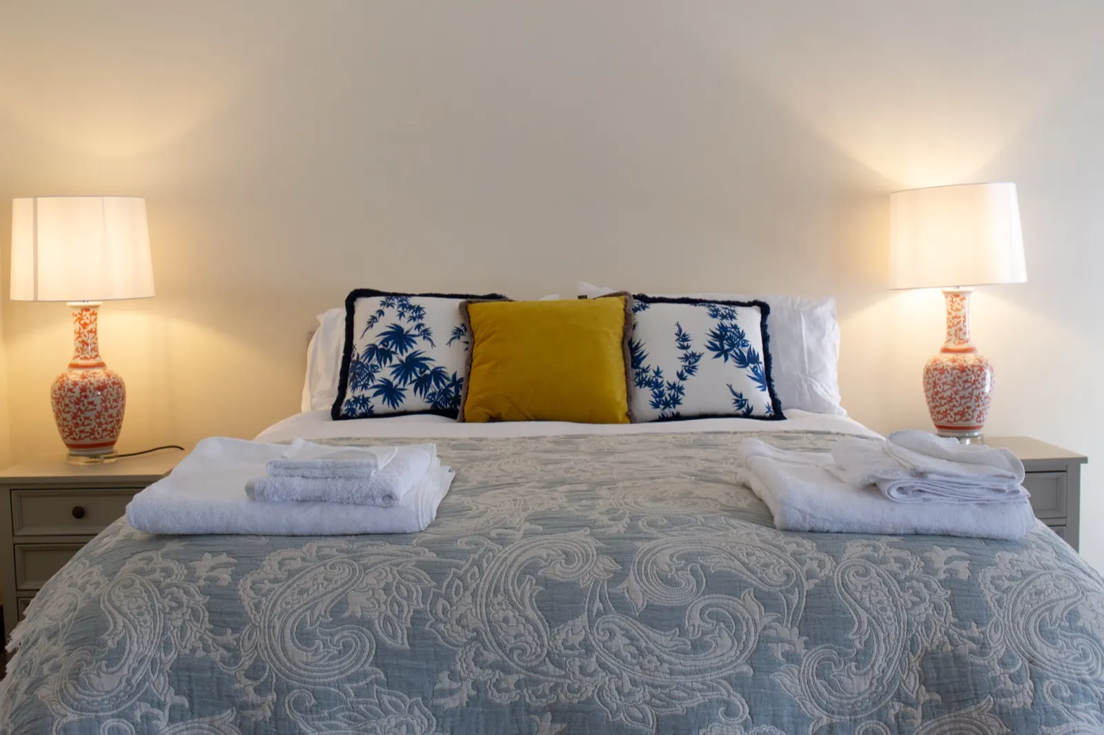 Double bedroom made up with fresh linen and towels, with a lamp on each bedside table