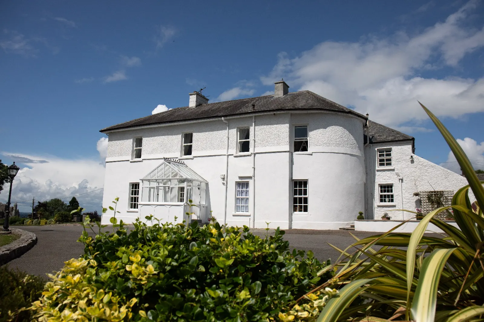 The white period house available for short-term letting, with a glazed porch and gravel forecourt